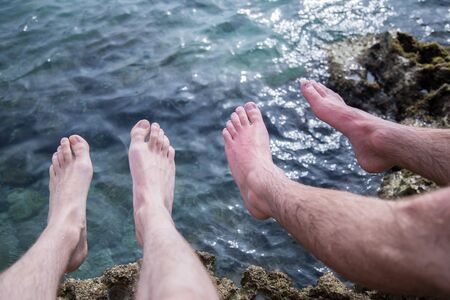 Legs of two men on the beach, relax