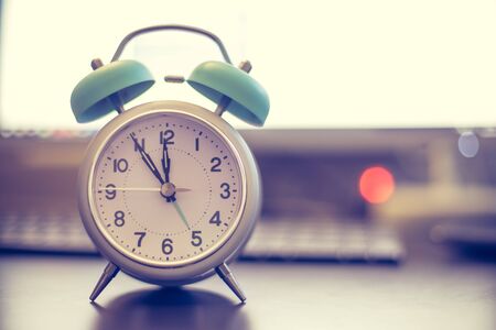 Alarm clock on the desk, office stuff in the blurry background, deadlines and todosの写真素材