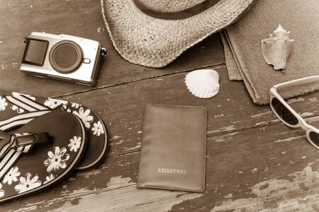 Summer background: Concept of leisure travel in the summer: Straw hat, sunglasses, flip flops, shells, vintage camera, towel and passport.の写真素材