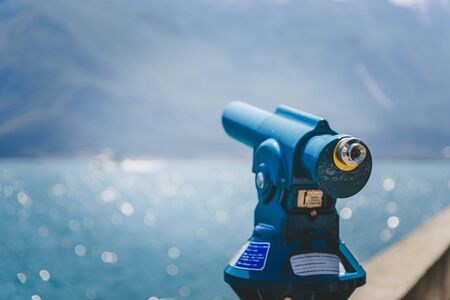 Close up of tourist binoculars at the lake Lago di Garda. Blue water and mountains in the blurry backgroundの写真素材