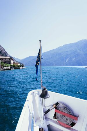 Bow of a boat on a boat tour. Blue water and mountain range, Lago di Garda, Italyの写真素材