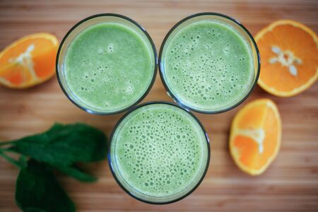 Arrangement of a fresh green healthy smoothies and fruits on a wooden background.の写真素材