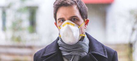 Young man outdoors with a breathing mask. Flue and corona season.の写真素材