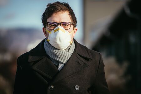 Young man outdoors with a breathing mask. Flue and corona seasonの写真素材