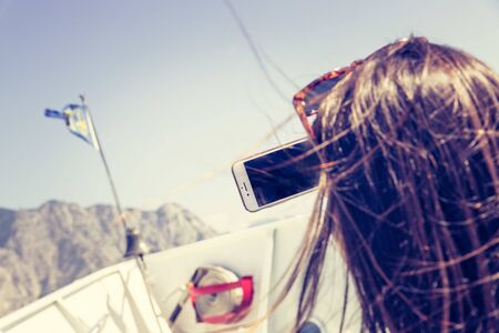 Tourists on a boat tour, taking pictures. Blue sky, white ship bow. Lago di garda, Italy