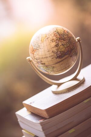 Miniature globe model standing on a stack of books. Symbol for travelling. の写真素材