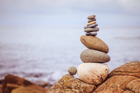 Close up picture of a stone cairn outdoors. Ocean in the blurry background