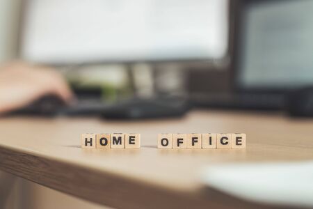 âHome Officeâ letters in foreground, man working in home office in blurry backgroundの写真素材