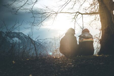 Loving couple enjoys the mountain view, beautiful scenery with sundown, autumnの写真素材