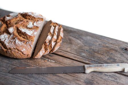 Fresh dark bread in slices. Rustic wooden cutting board and table, knife.