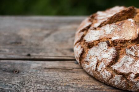Fresh dark bread on rustic cutting board, outdoorsの写真素材