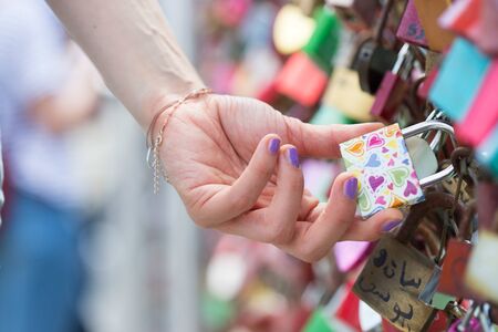 Girl with colorful nails is holding a love lock on Markatsteg, Salzburgの写真素材