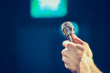 Person is holding up a metal microphone and wants to interview someone, copy space