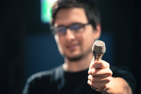 Young man on the stage is talking into a microphone, speech, face is blurryの写真素材