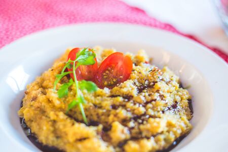 Fresh polenta with tasty tomatoes on a white plate, healthy mealの写真素材