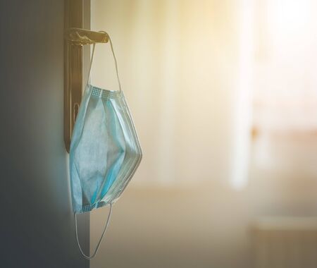Face mask or surgical mask is hanging on a door handle