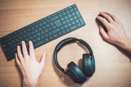 Wireless black headphones, mouse and keyboard on wooden desk