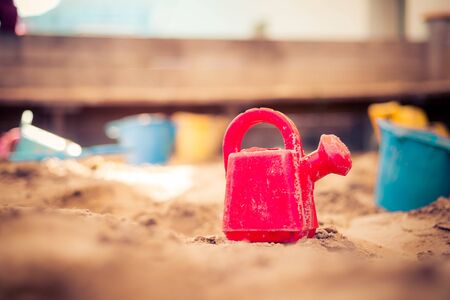 Children plastic toys in the sand box. Watering can, selective focus.の写真素材