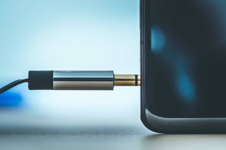 Connection 3.5mm audio jack to a black mobile phone. の写真素材