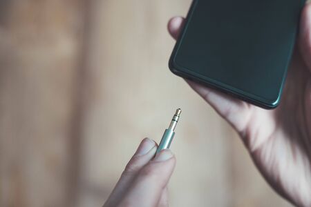 Connection 3.5mm audio jack to a black mobile phone. の写真素材