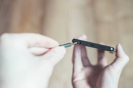 Connection 3.5mm audio jack to a black mobile phone. の写真素材