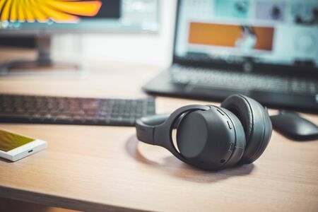 Wireless black headphones, mouse and keyboard on wooden desk