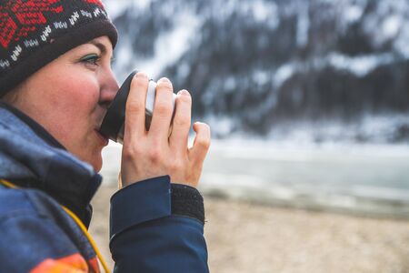 Beautiful Caucasian girl is holding a cup of tea outdoors, winter timeの写真素材