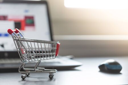 Online-Shopping concept: Miniature shopping cart, laptop and mouse in the blurry backgroundの写真素材