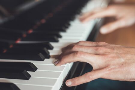 Man is playing piano at home. Clipping of piano and hands.