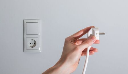 White plug with cable in males hand, ready to connect. Energy concept.の写真素材