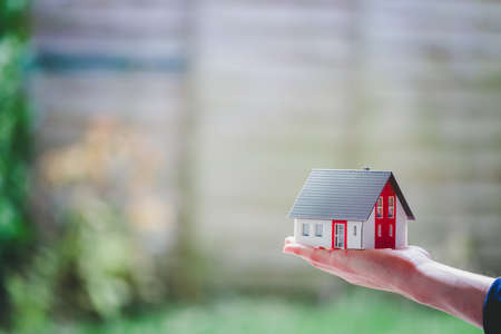New home and house concept: Red house model outdoors in male hand, copy spaceの写真素材