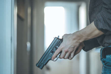 Undercover police agent is holding a black weapon in his hand, ready for shoot