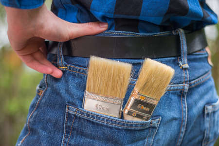 Close up picture of a craftsman with paint brushes in his pocketの写真素材