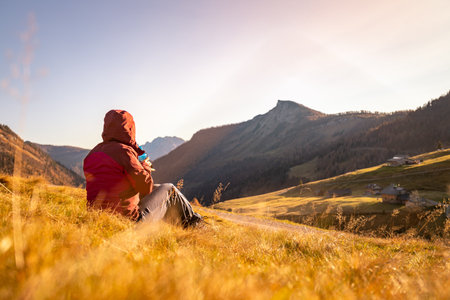 Woman in sportswear is enjoying the sunset in the mountains: sitting on the ground and enjoying the view. Alpes, Austriaの写真素材