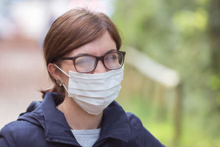 Young woman outdoors wearing a face mask and glasses, tarnished glassesの写真素材