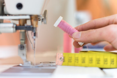 Close up of female hand holding a pink thread in a tailor workshopの写真素材