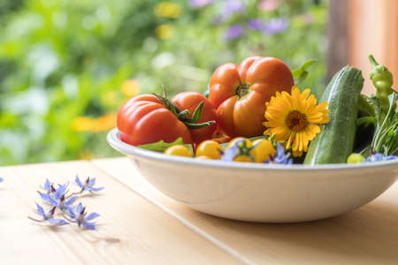 Fresh colorful vegetables in a bowl, raised in the own garden. Tomatoes, zucchini, flowers and herbs.の写真素材