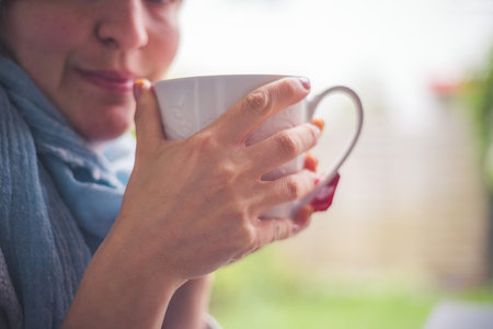 Young Caucasian woman is enjoying a cup of tea on the verandaの写真素材