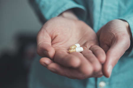 Male hand holding drug or vitamin pill inの写真素材
