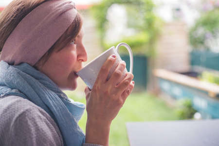 Young Caucasian woman is enjoying a cup of tea on the verandaの写真素材