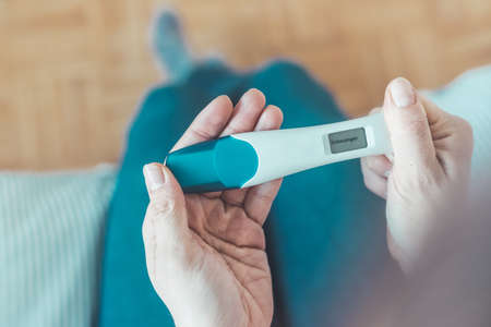 Middle age woman hand is holding pregnancy test, result is pregnant, "Schwanger"の写真素材