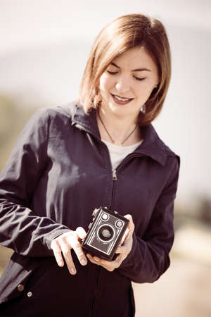 Cute girl is making pictures with a vintage camera, outsideの写真素材