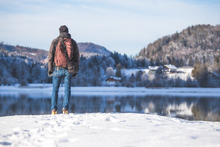 Sporty Caucasian man is at the lakeshore, enjoying the view. Winter landscape.の写真素材