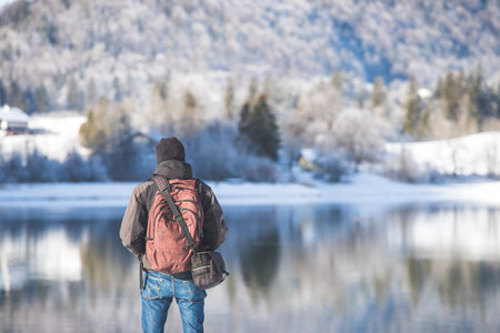 Sporty Caucasian man is at the lakeshore, enjoying the view. Winter landscape.の写真素材