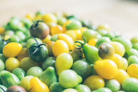 Close up of cocktail tomatoes on wooden plate, yellow and greenの写真素材