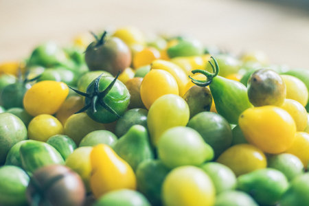 Close up of cocktail tomatoes on wooden plate, yellow and greenの写真素材