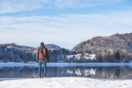 Sporty Caucasian man is at the lakeshore, enjoying the view. Winter landscape.の写真素材