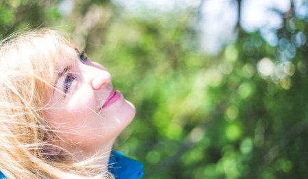 Portrait of attractive young girl outdoors, spring time, blurry green backgroundの写真素材