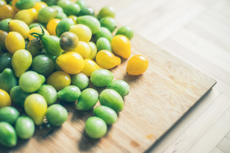 Close up of cocktail tomatoes on wooden plate, yellow and greenの写真素材