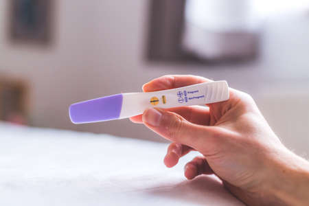 Woman hand holding pregnancy test, result is pregnantの写真素材